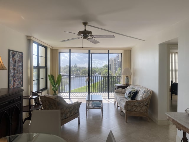 living room featuring floor to ceiling windows, a water view, and ceiling fan