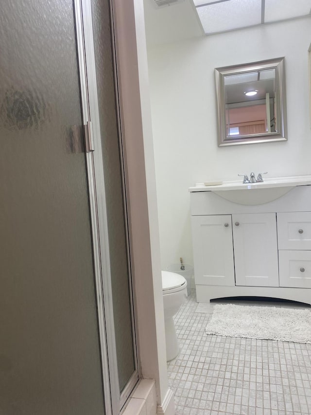 bathroom featuring tile patterned floors, a shower with door, vanity, and toilet