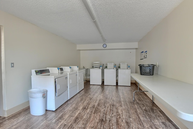 clothes washing area with washer and dryer, wood-type flooring, and a textured ceiling