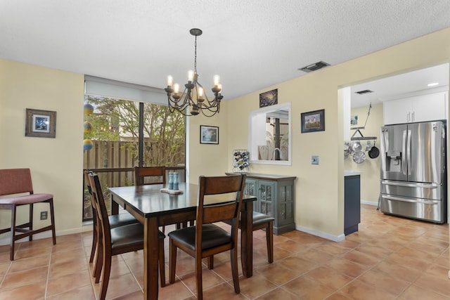 tiled dining area with a notable chandelier and a textured ceiling