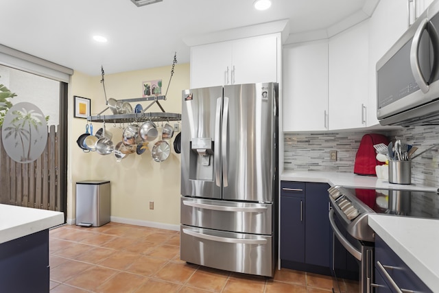 kitchen with appliances with stainless steel finishes, white cabinetry, tasteful backsplash, light tile patterned floors, and blue cabinets