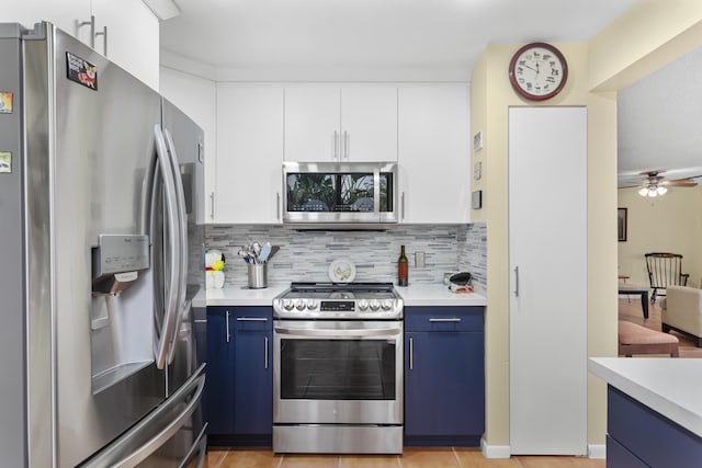 kitchen with stainless steel appliances, blue cabinetry, white cabinets, and backsplash