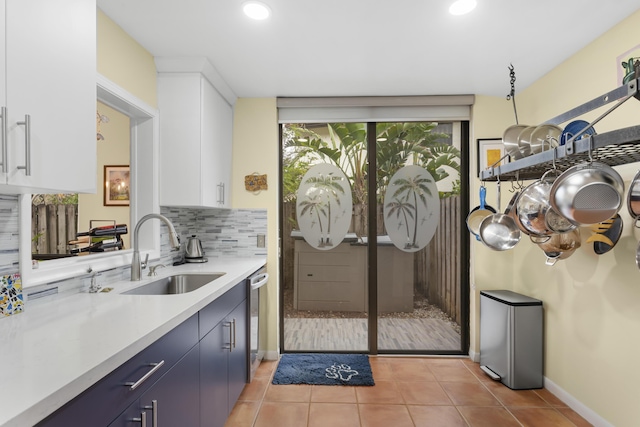 kitchen with backsplash, dishwasher, sink, white cabinetry, and blue cabinetry