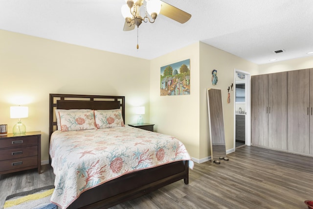 bedroom featuring dark wood-type flooring, ceiling fan, and a textured ceiling