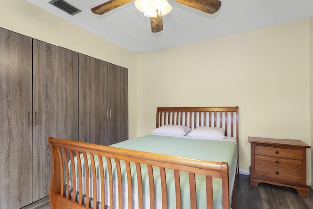 bedroom with ceiling fan, dark wood-type flooring, and a textured ceiling