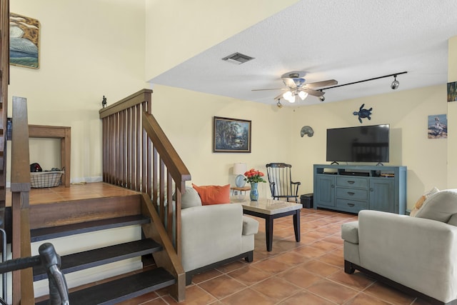 tiled living room featuring ceiling fan and a textured ceiling