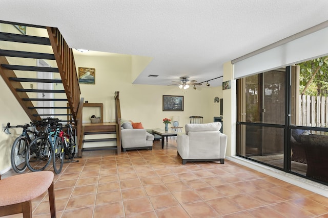 tiled living room with ceiling fan, track lighting, and a textured ceiling