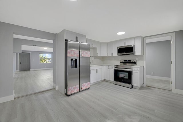 kitchen featuring white cabinets, appliances with stainless steel finishes, light wood-type flooring, and sink