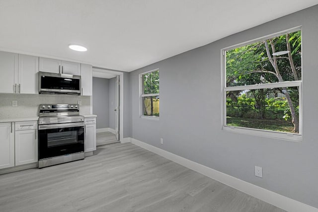 kitchen with white cabinets, a healthy amount of sunlight, stainless steel appliances, and light hardwood / wood-style flooring