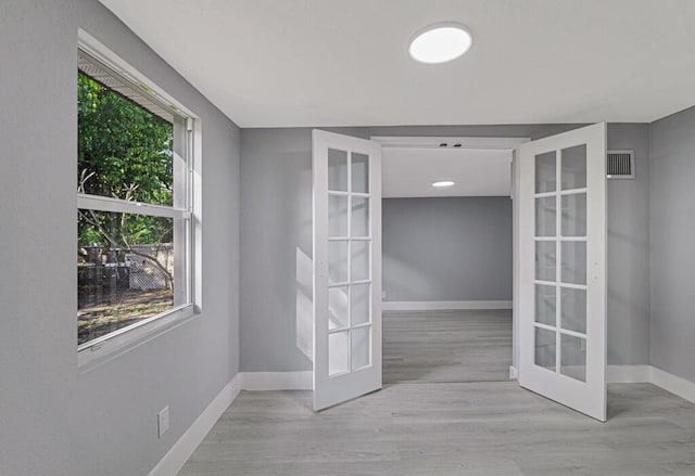 spare room with plenty of natural light, light wood-type flooring, and french doors