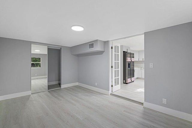 basement with stainless steel fridge with ice dispenser and light hardwood / wood-style flooring