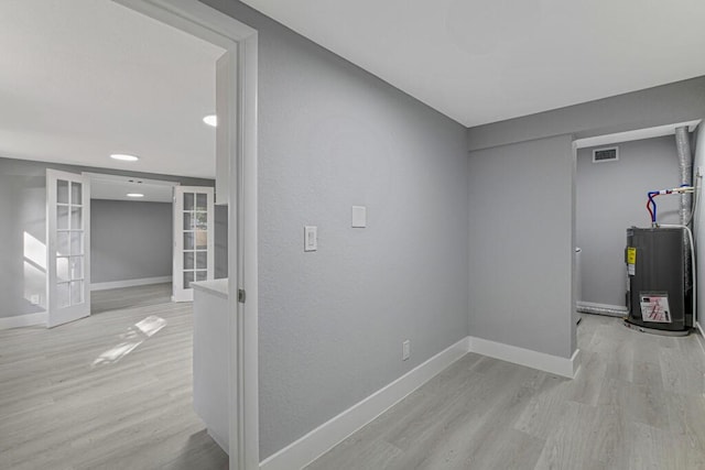 interior space featuring water heater, french doors, and light hardwood / wood-style flooring