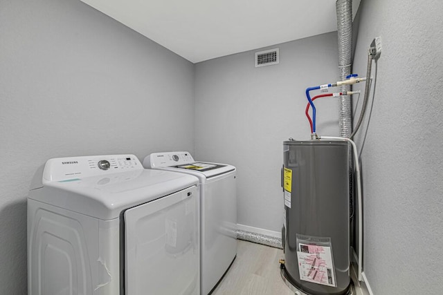 laundry room featuring separate washer and dryer, light hardwood / wood-style flooring, and water heater