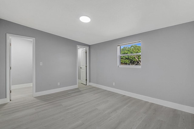 spare room featuring lofted ceiling and light wood-type flooring