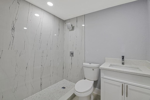 bathroom featuring a tile shower, vanity, and toilet