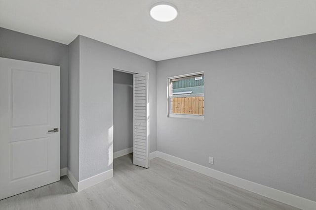 unfurnished bedroom with light wood-type flooring and a closet