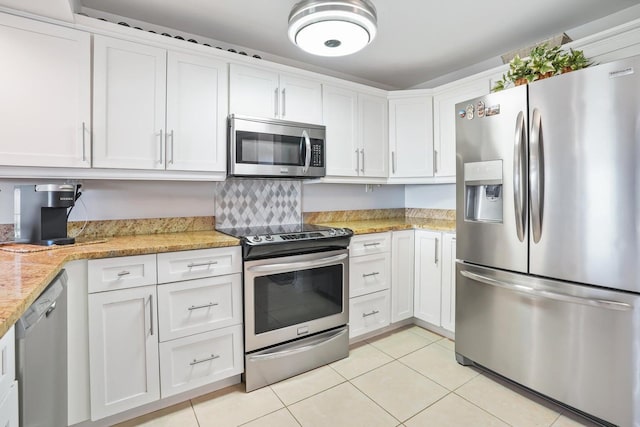 kitchen with light stone counters, white cabinets, light tile patterned floors, and appliances with stainless steel finishes