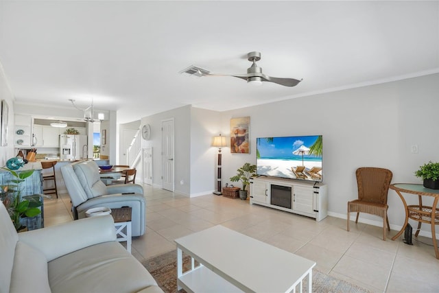 living room featuring ceiling fan with notable chandelier, light tile patterned floors, and ornamental molding