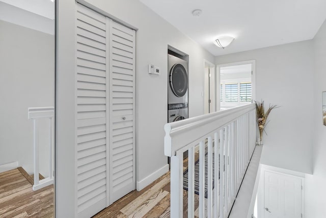 hallway featuring hardwood / wood-style flooring and stacked washer / dryer