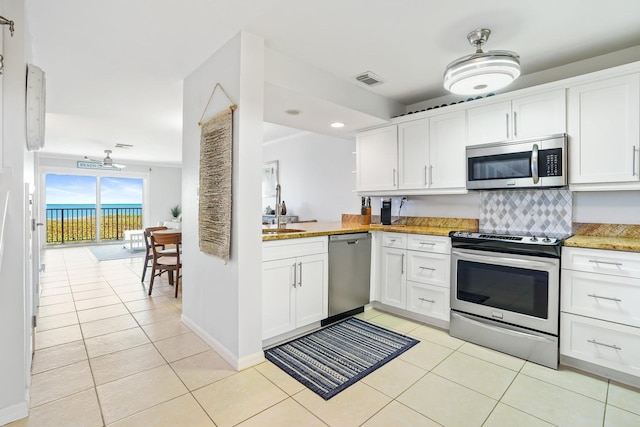 kitchen featuring sink, tasteful backsplash, light tile patterned flooring, white cabinetry, and stainless steel appliances