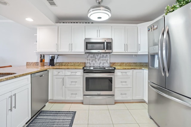 kitchen with white cabinets, light tile patterned floors, light stone countertops, appliances with stainless steel finishes, and kitchen peninsula