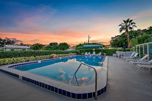 pool at dusk featuring a patio