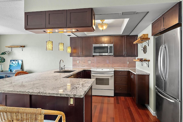 kitchen featuring kitchen peninsula, light stone countertops, stainless steel appliances, sink, and hanging light fixtures