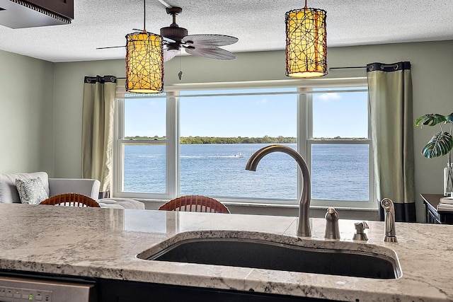 kitchen with ceiling fan, sink, decorative light fixtures, a water view, and dishwasher