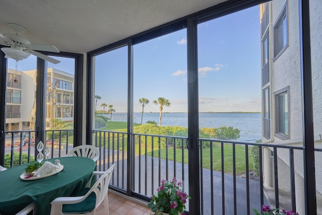 sunroom / solarium with ceiling fan and a water view