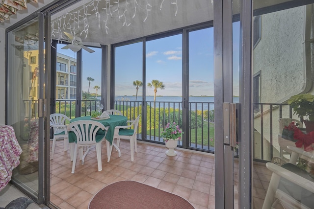 sunroom / solarium with ceiling fan and a water view