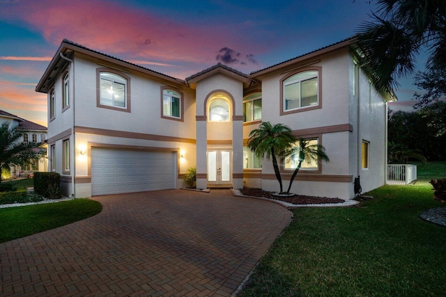 view of front of property featuring french doors, a garage, and a lawn