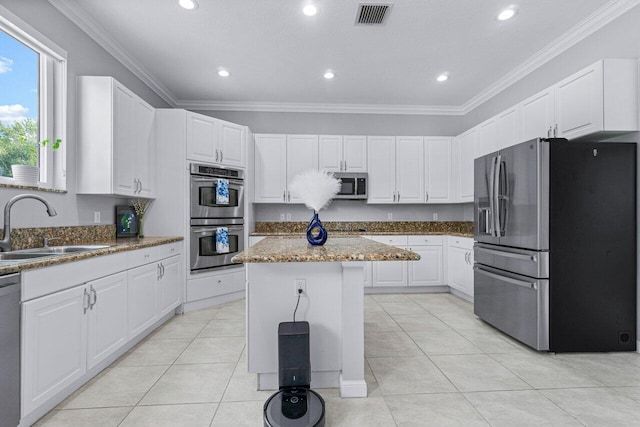 kitchen with light stone countertops, sink, stainless steel appliances, a kitchen island, and white cabinets