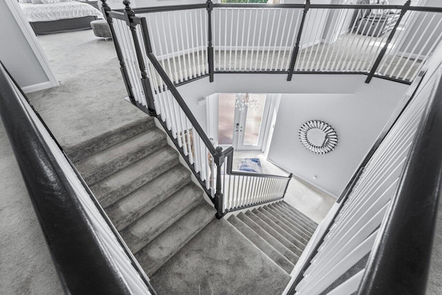 stairway featuring french doors, carpet floors, and a notable chandelier