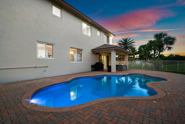 pool at dusk featuring a patio area