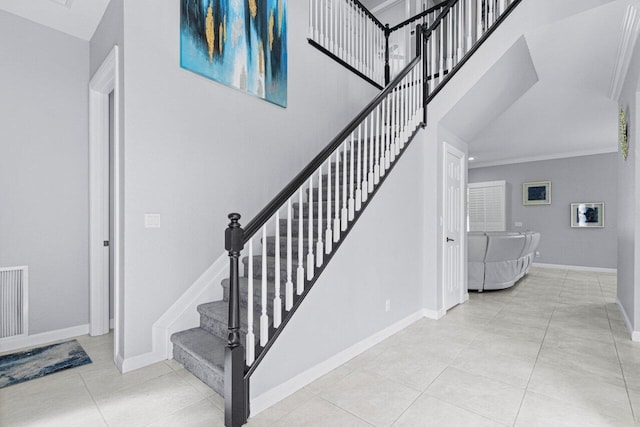 stairs featuring a towering ceiling, tile patterned floors, and crown molding