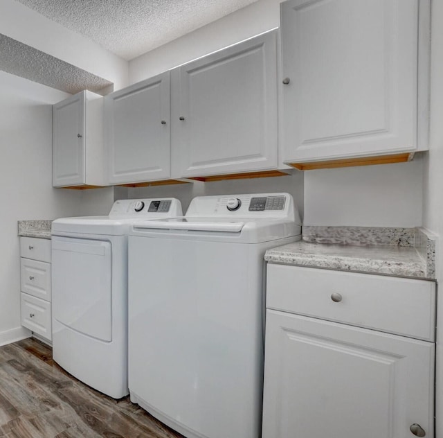 laundry room featuring washing machine and dryer, hardwood / wood-style floors, cabinets, and a textured ceiling