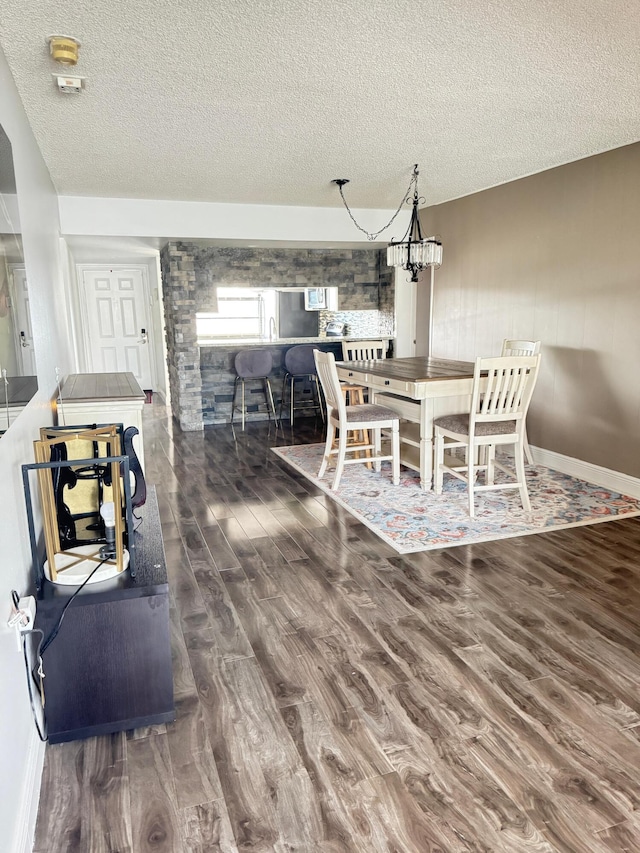 dining area featuring dark hardwood / wood-style flooring, a textured ceiling, and a notable chandelier