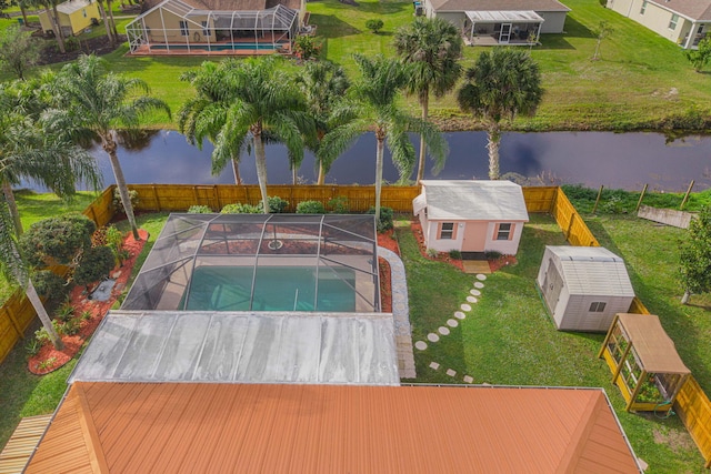 view of swimming pool with glass enclosure, a water view, and an outdoor structure