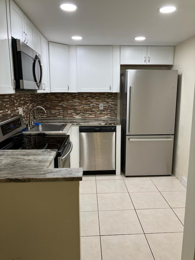 kitchen featuring appliances with stainless steel finishes, tasteful backsplash, sink, light tile patterned floors, and white cabinetry