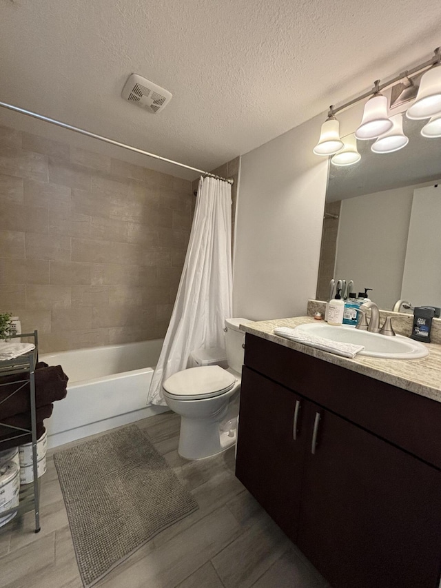 full bathroom featuring shower / bath combination with curtain, toilet, a textured ceiling, and vanity