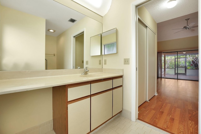 bathroom with wood-type flooring, vanity, a textured ceiling, and ceiling fan