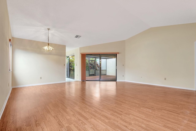 spare room featuring a notable chandelier, lofted ceiling, and light hardwood / wood-style flooring