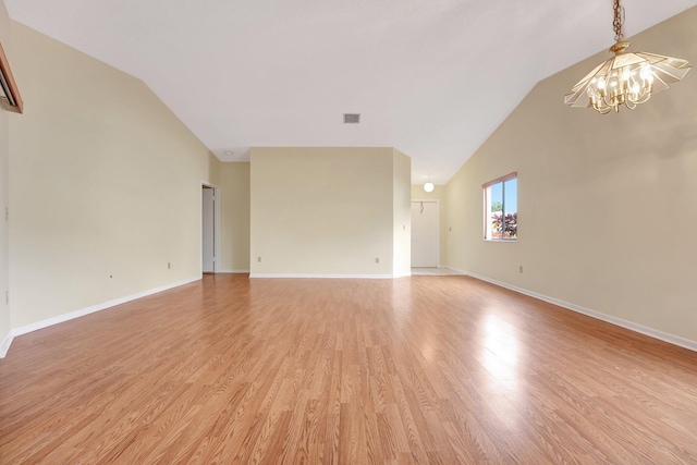 unfurnished living room featuring hardwood / wood-style floors, vaulted ceiling, and a chandelier