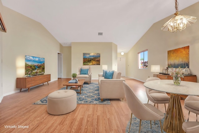 living room with a chandelier, light wood-type flooring, and lofted ceiling