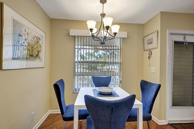 dining room with a notable chandelier, wood-type flooring, and a textured ceiling