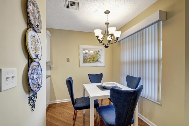 dining area featuring a chandelier, hardwood / wood-style floors, and a textured ceiling