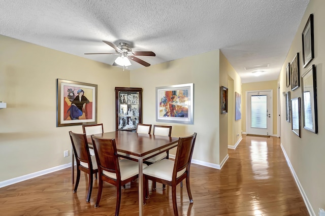 dining room featuring dark hardwood / wood-style floors, ceiling fan, and a textured ceiling