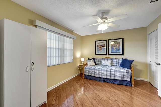 bedroom with ceiling fan, a closet, light hardwood / wood-style floors, and a textured ceiling