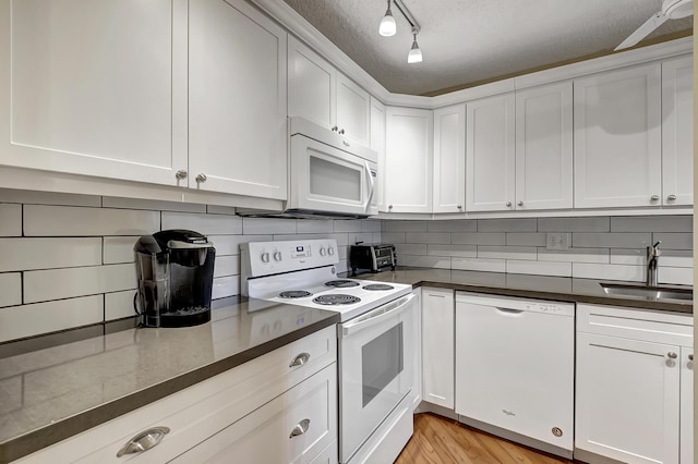 kitchen featuring a textured ceiling, sink, white cabinets, and white appliances