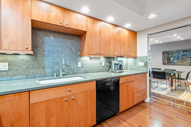 kitchen featuring backsplash, sink, black dishwasher, and light hardwood / wood-style flooring